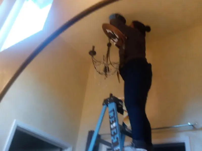 Electrician installing a chandelier in a Surrey residence